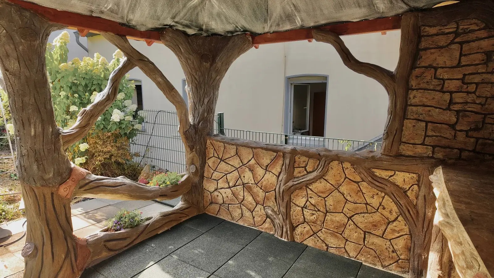 Brüstung in Natursteinoptik mit Ästen in Holzoptik